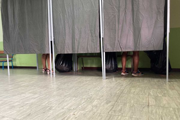 Les premiers électeurs choisissent leur bulletin de vote dans les isoloirs de ce bureau de vote, à Saint-Joseph