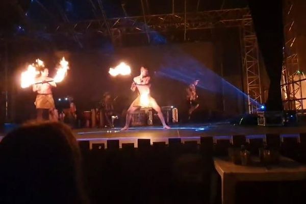 Une spectatrice filme la performance. L'incendie prend à l'arrière de la scène.