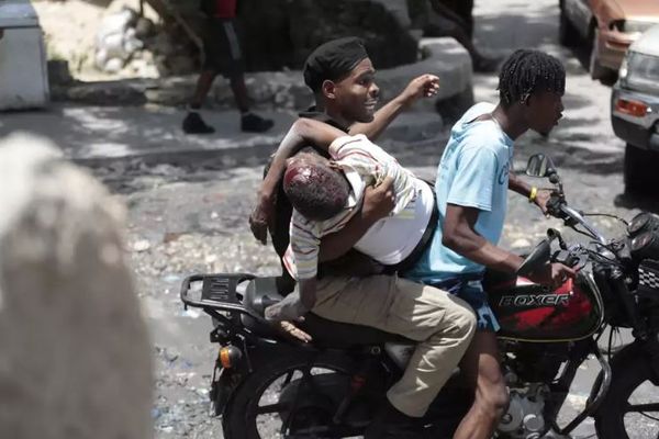 Un policier tient un homme blessé lors de violents affrontements entre gangs dans le quartier Carrefour-Feuilles de Port-au-Prince, le 15 août 2024.