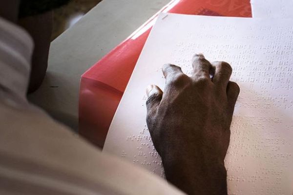 Un homme lit un document écrit en braille (illustration).