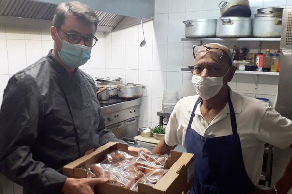 Damien Delbart livrant des saucisses fumées à Sylvain Gaungoo, gérant de la Charrette Créole (Paris VIème).