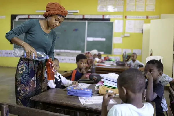 Une enseignante remplit une gourde lors d'une distribution d'eau dans une école de Trevani, à Mayotte.