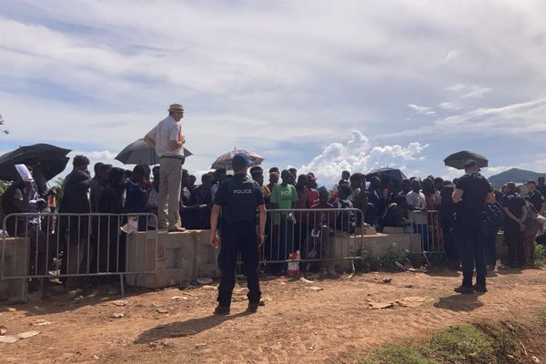 Les migrants rassemblés derrière une barrière durant le démantèlement du camp de Tsoundzou ce vendredi 14 février