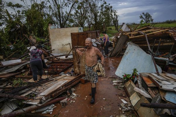 Une famille tente de recuperer quelques affaires dans leur maison détruite par l'ouragan Rafael