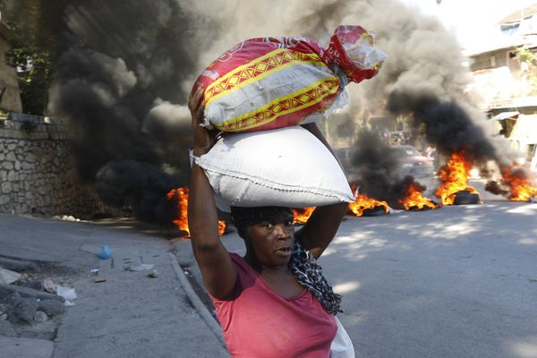 Une femme passe devant des pneus en feu, incendiés par des manifestants, pour attirer l'attention sur l'insécurité du pays et exiger la démission du premier ministre - Port-au-Prince (Haïti) - 18/01/2024.