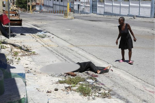 Une femme regarde un corps gisant dans la rue, dans le quartier Delmas de Port-au-Prince (Haïti) - 04/09/2024.