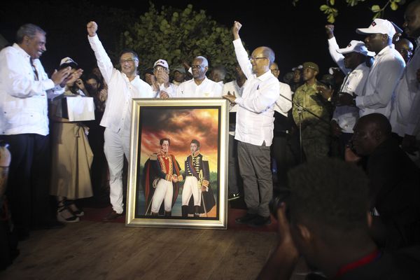 Le président colombien Gustavo Petro, à gauche, Leslie Voltaire, président du Conseil de transition d'Haïti, à droite, lèvent le poing avec une peinture de Simon Bolivar et Alexandre Pétion à Jacmel, Haïti, le mercredi 22 janvier 2025. Au centre, Edgard Leblanc Fils, ancien président du Conseil.