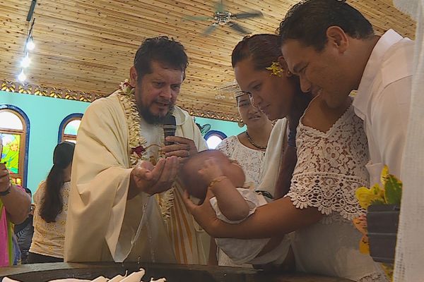 Père Auguste baptisant un bébé à la demande des parents.