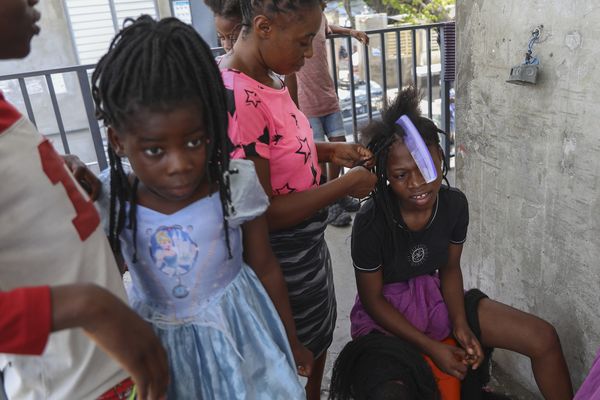 Une femme tresse les cheveux d'une fille dans une école qui sert de refuge aux personnes déplacées par la violence des gangs, à Port-au-Prince (Haïti) - 13/08/2024.