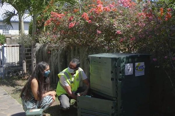 Un animateur environnement explique à Shannti Dinnoo l'utilisation du composteur