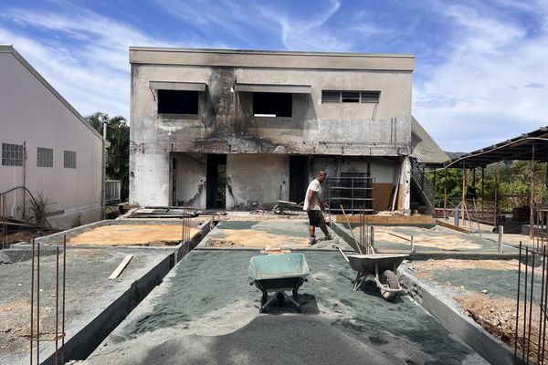 Un ouvrier face à un bâtiment incendié à Païta.