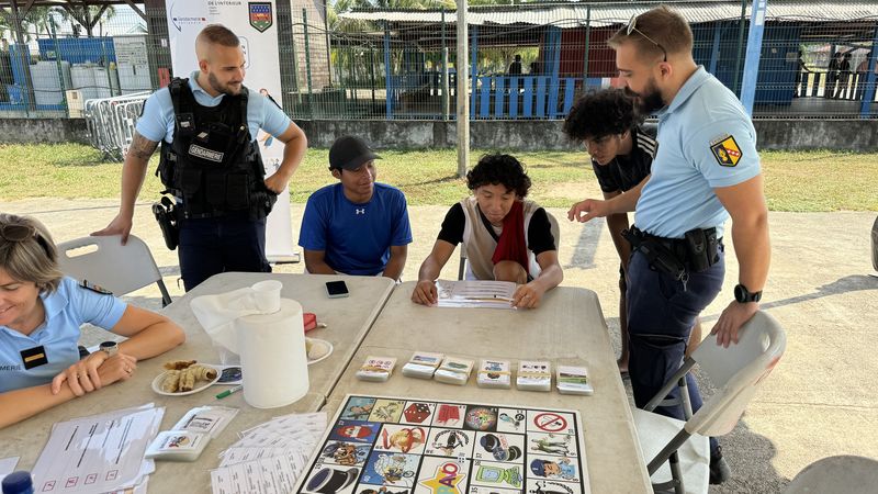 The gendarmes of Saint-Laurent-du-Maroni talk with participants in the youth festival in Javouhey, presenting them with an educational game to prevent risks related to alcohol